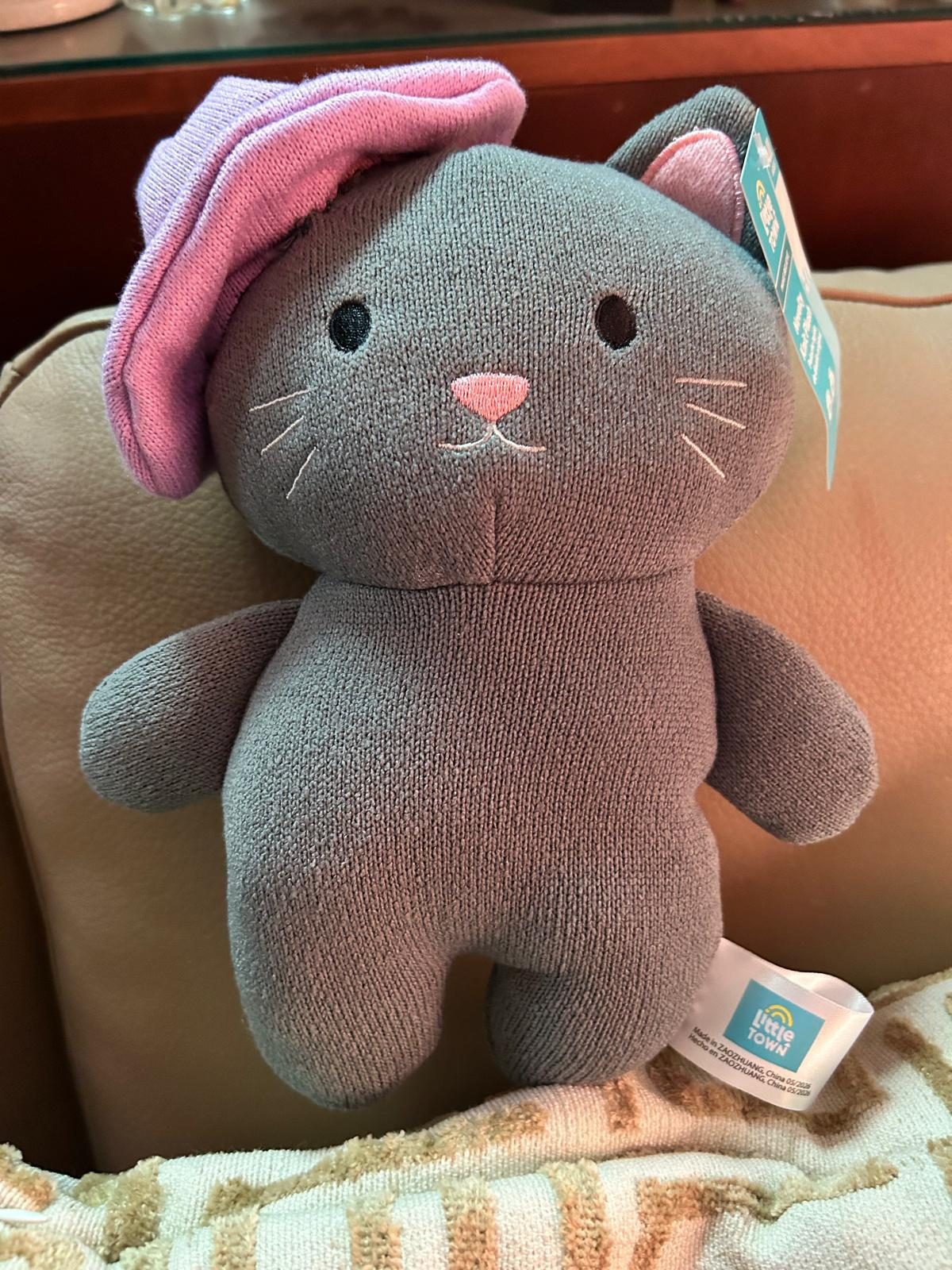 Grey stuffed toy cat wearing a pink hat, the putty tat with a hat