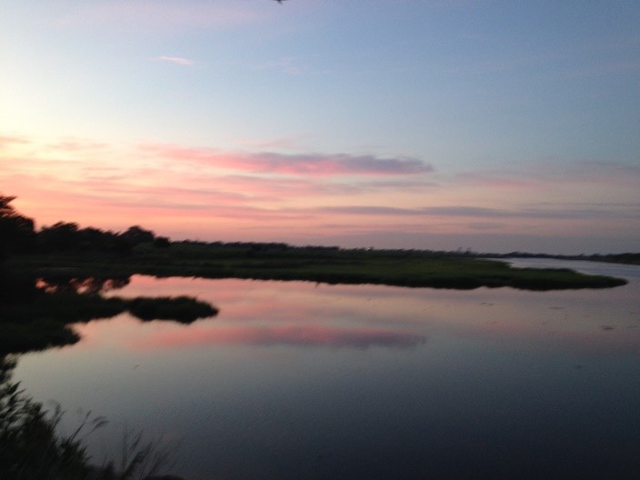 Heart shaped clouds at sunset reflected over water